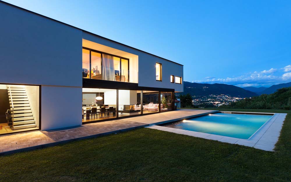 A modern villa style home with mountain and city lights in the back ground.