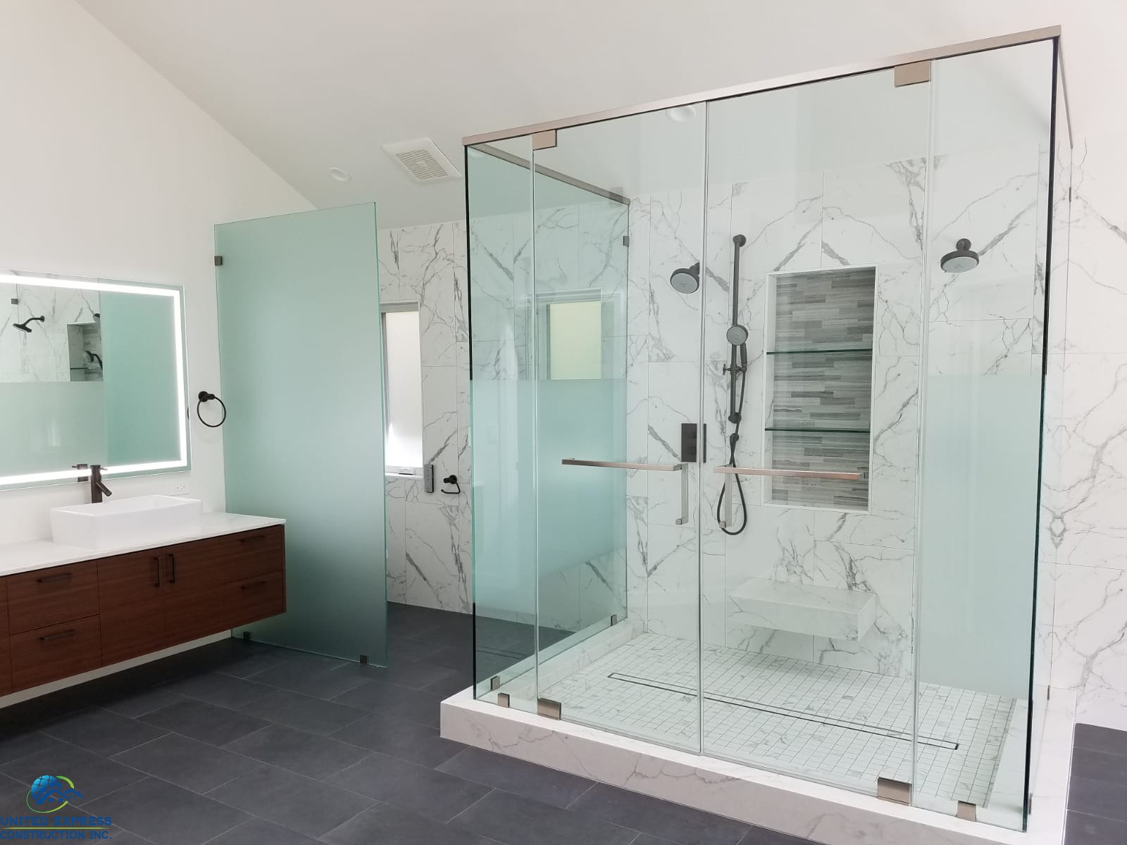 A modern bathroom with marble walled shower enclosure