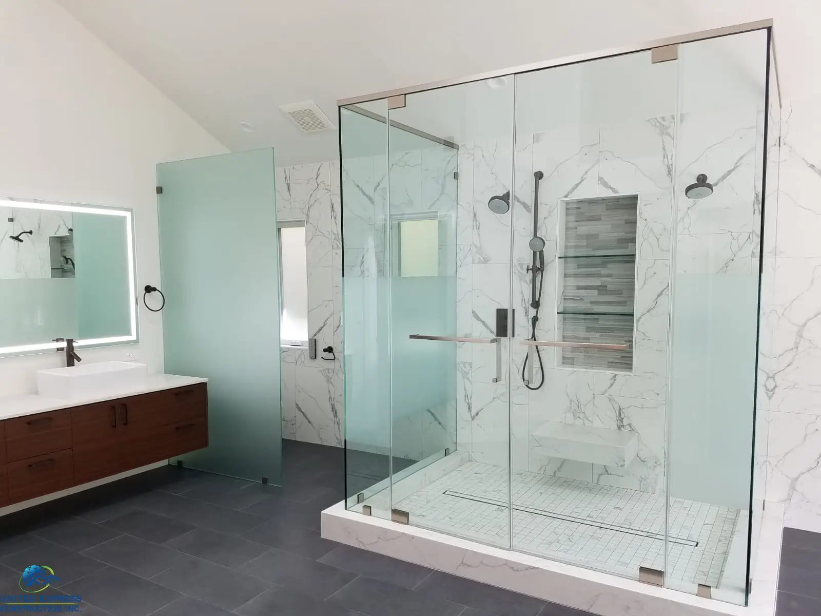 A modern bathroom with marble walled shower enclosure