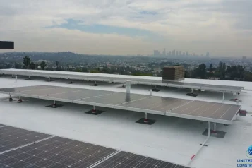 An Image of a roof with solar panels on it with the LA City scape in the back ground